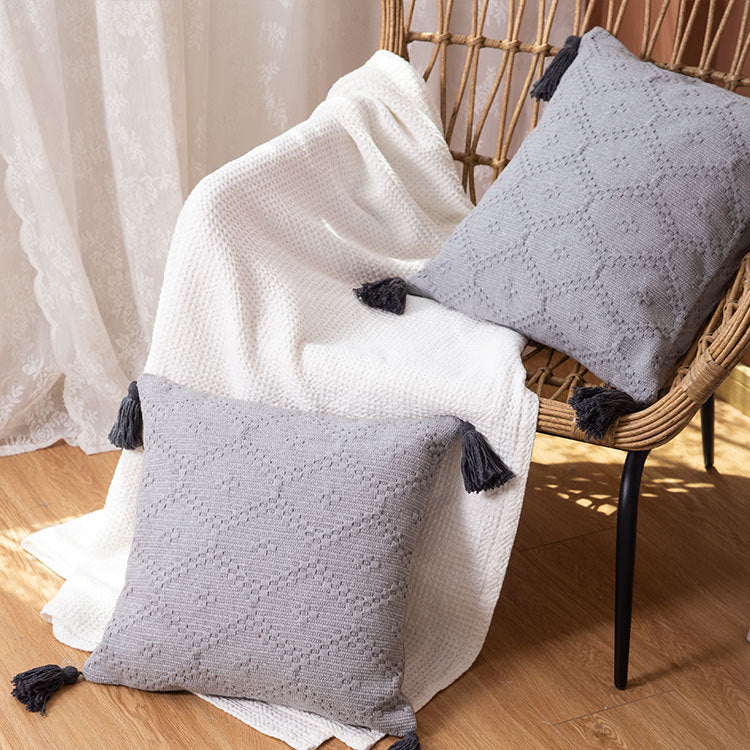 Decorative cushion cover made of woven cotton blend with tactile diamond structure and contrast tassels