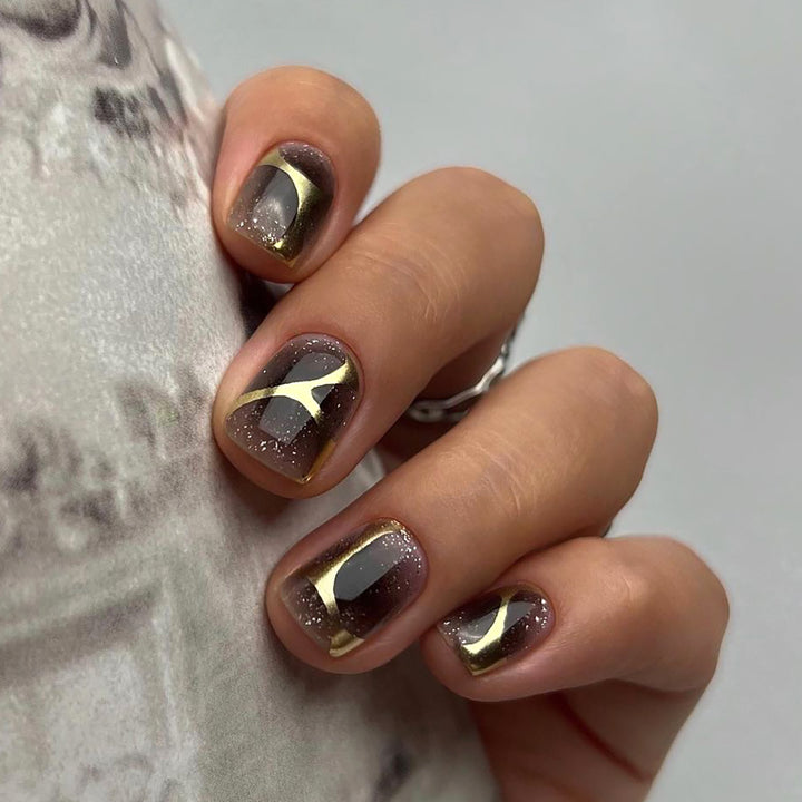 Artificial nail art with elegant metallic design and glitter accents Stornfield
