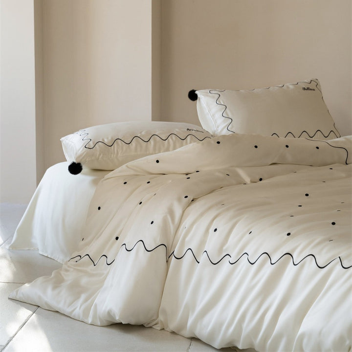Bedding set made of cotton satin with wavy embroidery edge and pompom cushion
