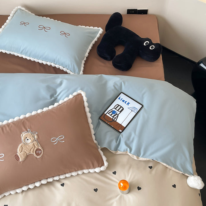 Children's bed set with teddy bear embroidery, pom-pom edging, and reversible blanket