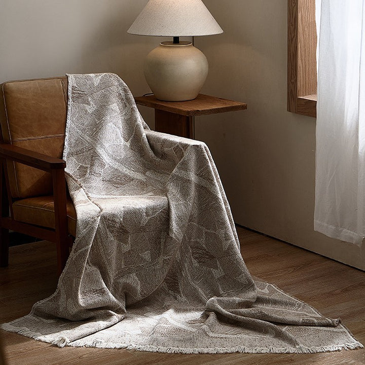 Large cozy living blanket made of cotton blend fabric with geometric jacquard pattern and fringed hem