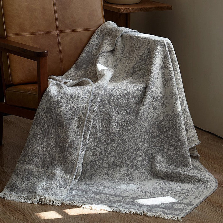 Large cozy living blanket made of cotton blend fabric with geometric jacquard pattern and fringed hem