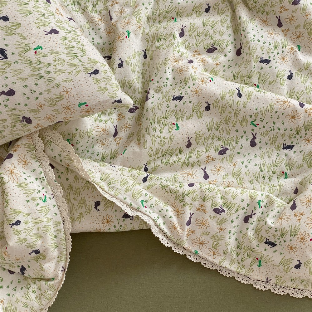 Quilted throw blanket made of cotton blend with delicate floral pattern and lace edge