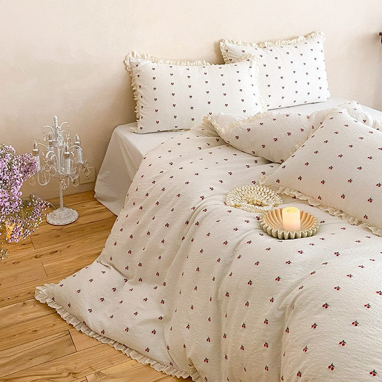 Quilted bedding set made of cotton muslin with delicate cherry print and ruffle edge