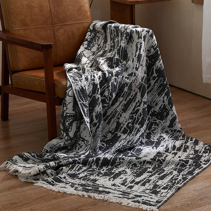 Large cozy living blanket made of cotton blend fabric with geometric jacquard pattern and fringed hem
