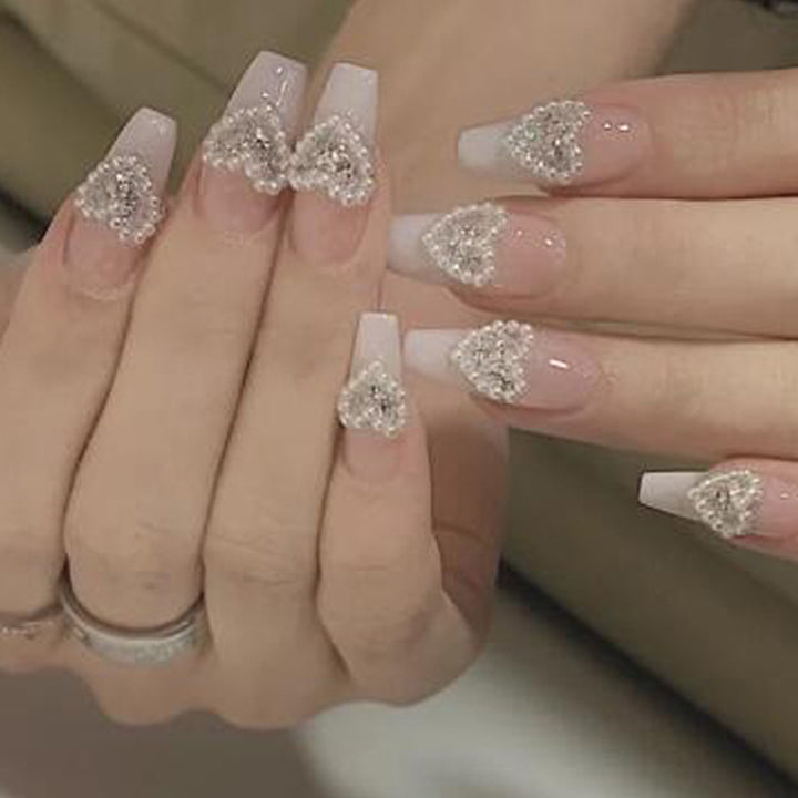 Artificial nail art with heart and rhinestone decorations Stornfield