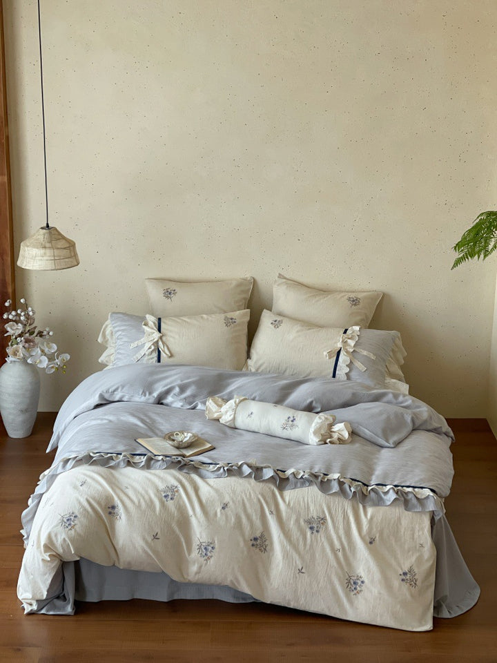 Romantic cotton satin bedding set with ruffles, embroidered flower bouquets, and decorative rolls Stornfield
