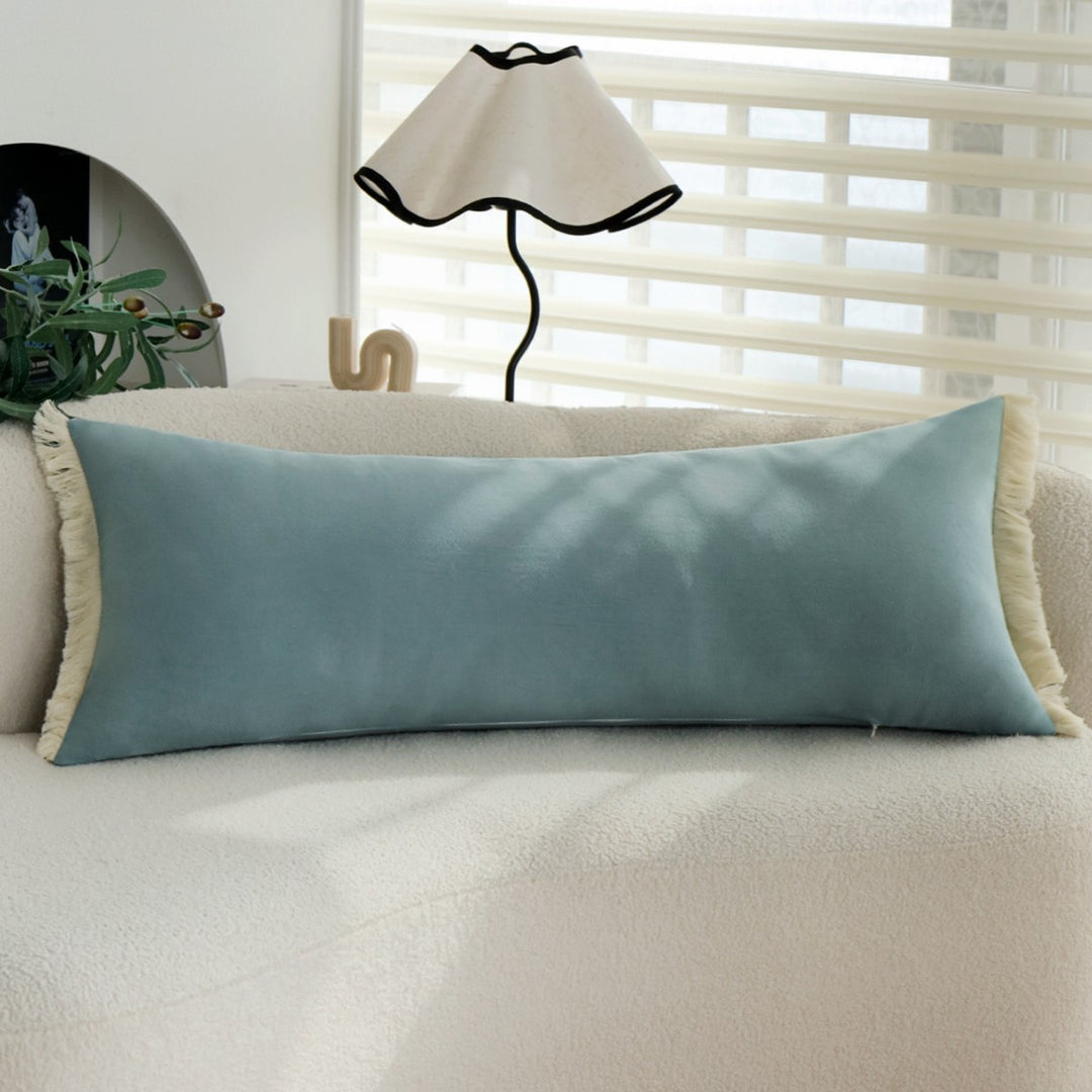 elongated decorative cushion with fringes and velvety surface