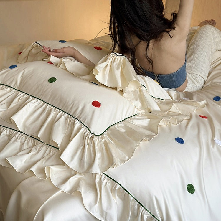 Bedding set with embroidered dots, decorative ruffles, and fine piping
