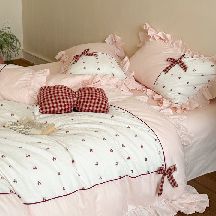 Playful ruffled bed set made of cotton muslin with embroidered cherries and checkered bows