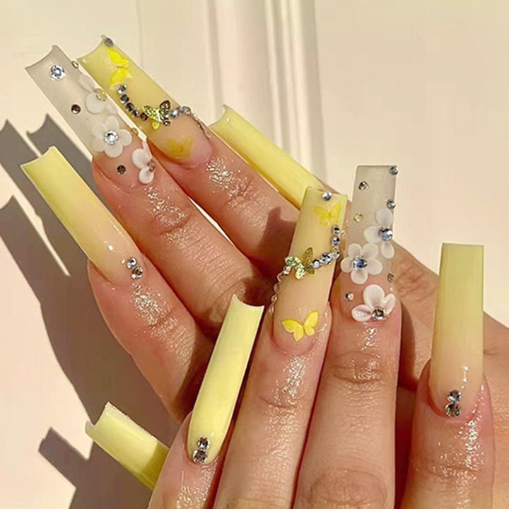Artificial nail extensions with floral accents and rhinestones Stornfield
