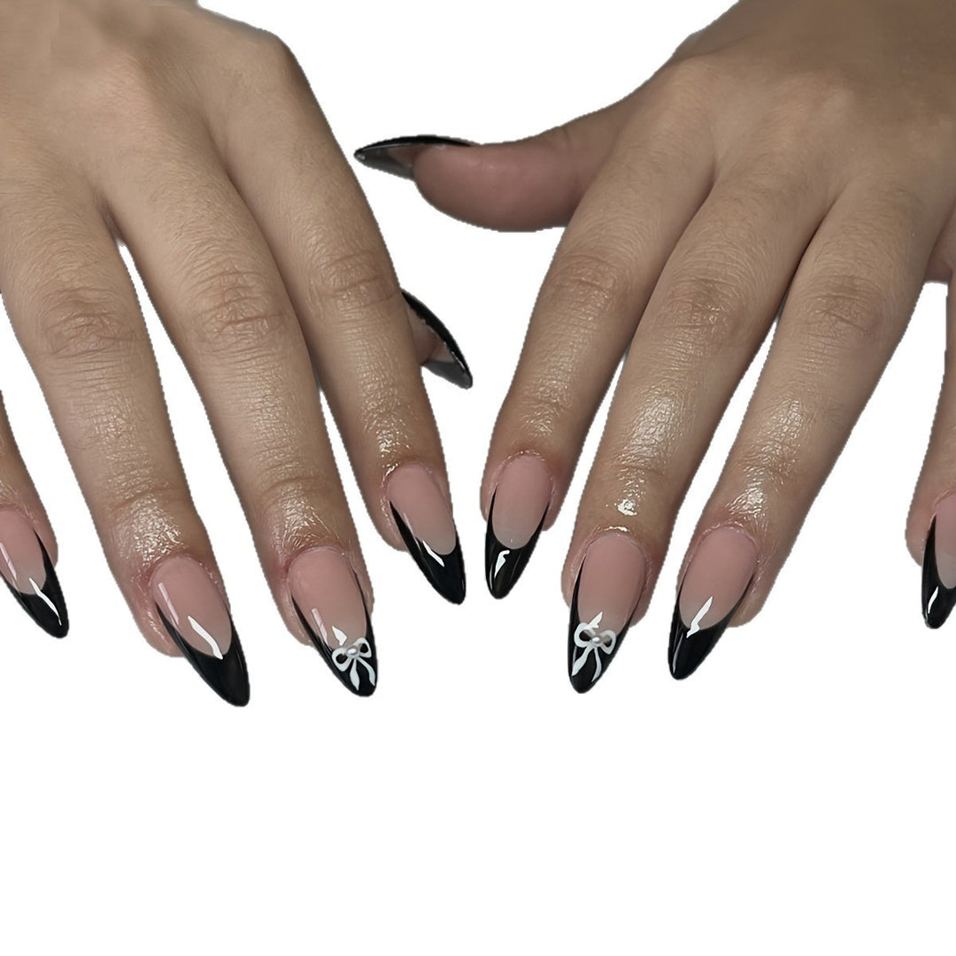 Acrylic nail set with elegant black and white design and cute bow accents Stornfield