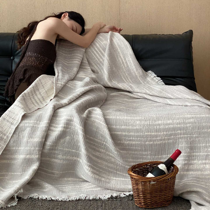 Cozy living blanket made of cotton blend fabric with fringes and striped texture
