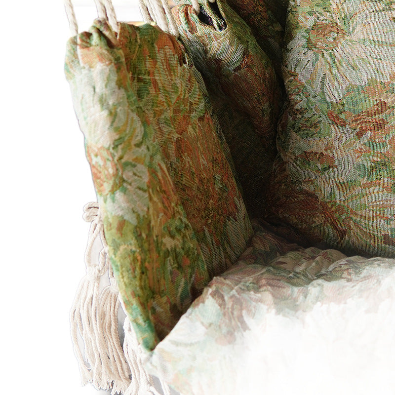 Woven hammock chair with padded floral cushions and macramé fringe Stornfield