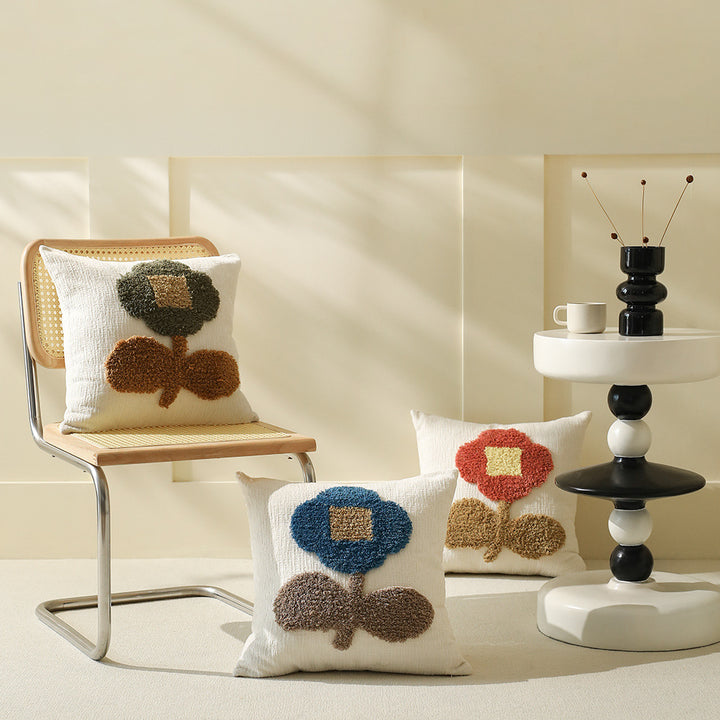 Square decorative pillow with hand-tufted floral appliqué and textured linen look