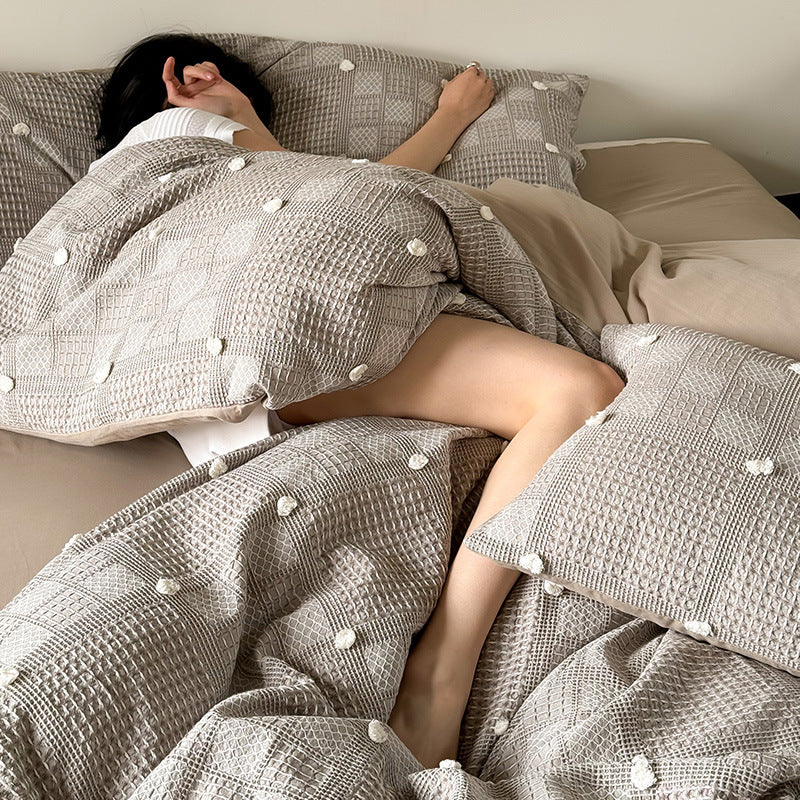 Luxurious cotton bedding set with textured waffle appearance and pompom details
