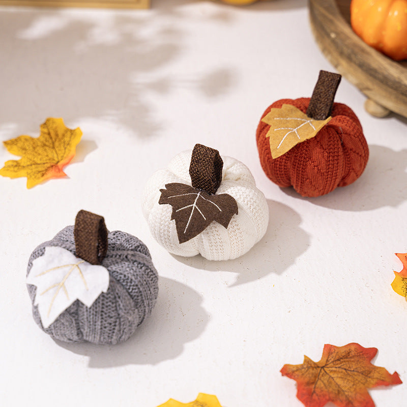 Knitted fabric pumpkin as autumn table decoration with felt leaf