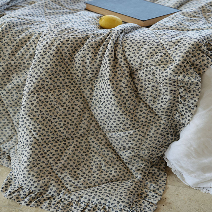 Lightly quilted throw blanket in vintage floral print with ruffled edge