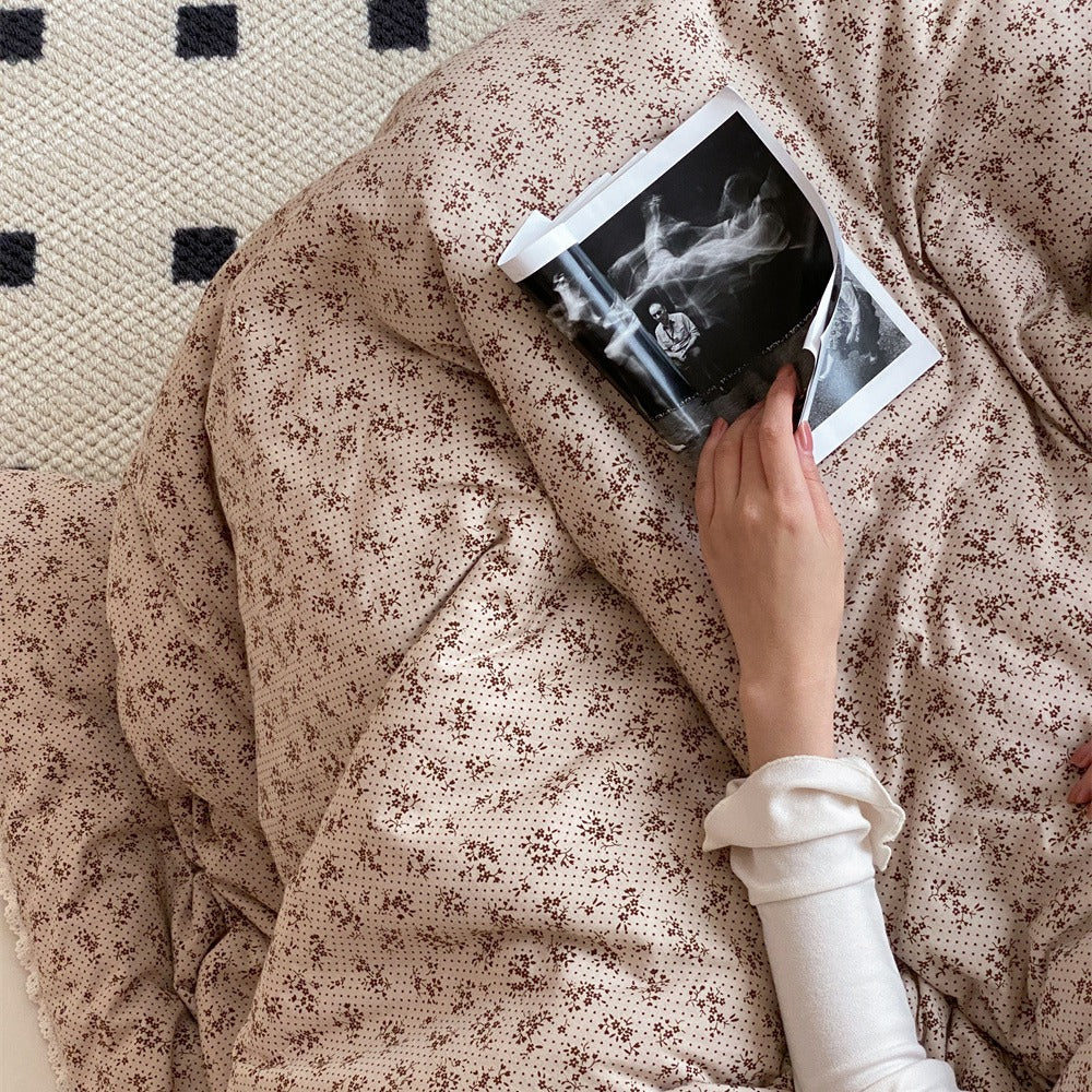 Quilted throw blanket made of cotton blend with delicate floral pattern and lace edge