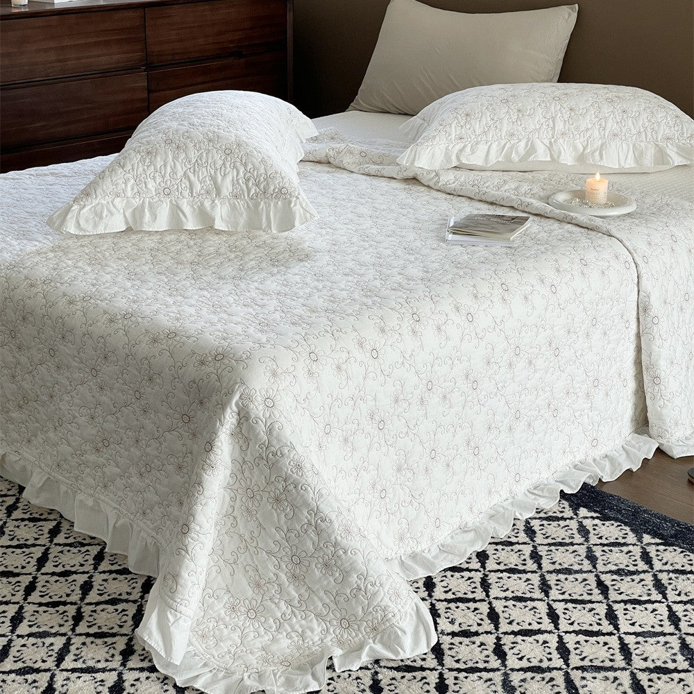 Padded quilted bedspread with a floral all-over pattern and ruffled edges