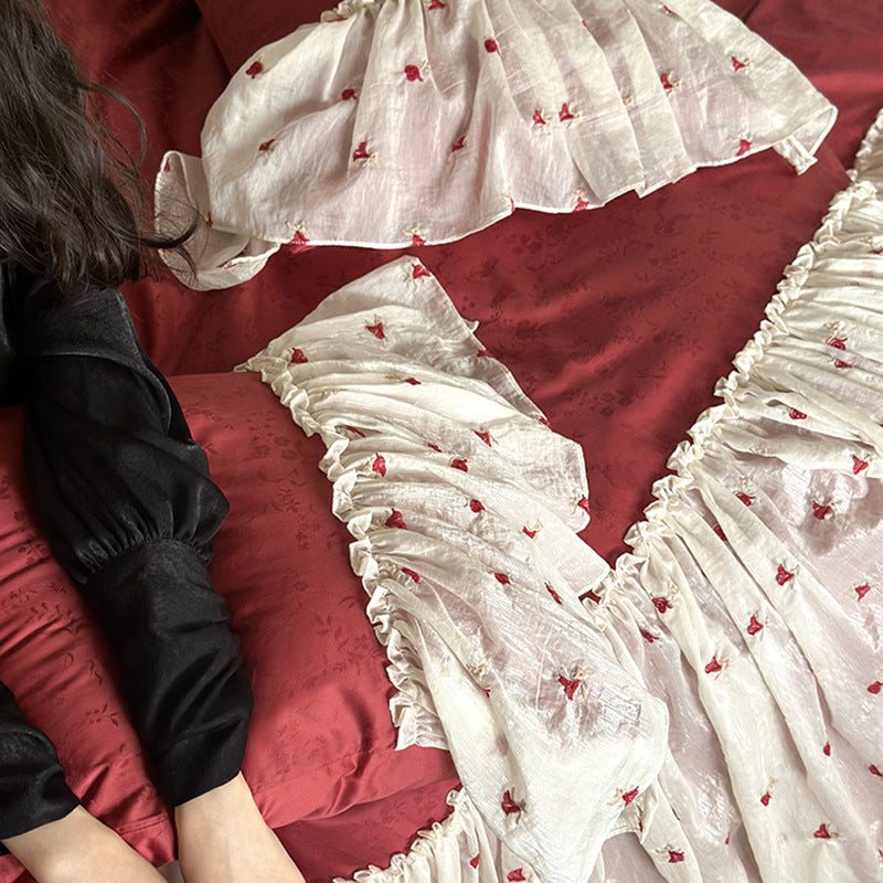 Ruffled bedskirt and pillowcases made of embroidered cotton-linen blend