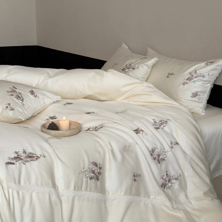 Satin bedding set with subtly embroidered flowers and lace trim