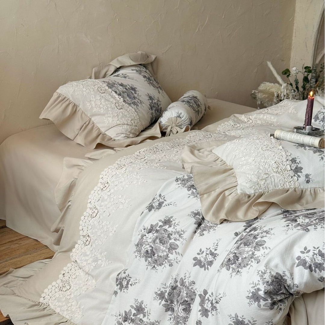 Bedding set in French country house style with lace trim, ruffled bed skirt, and subtle toile floral design