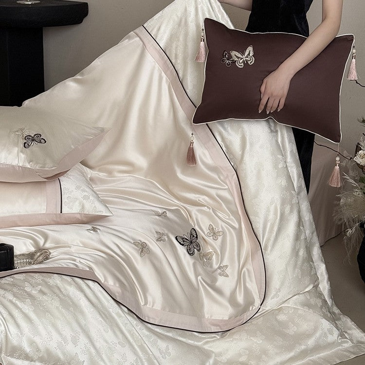 Luxurious satin bedding set with embroidered butterflies, decorative pillows, and tassels