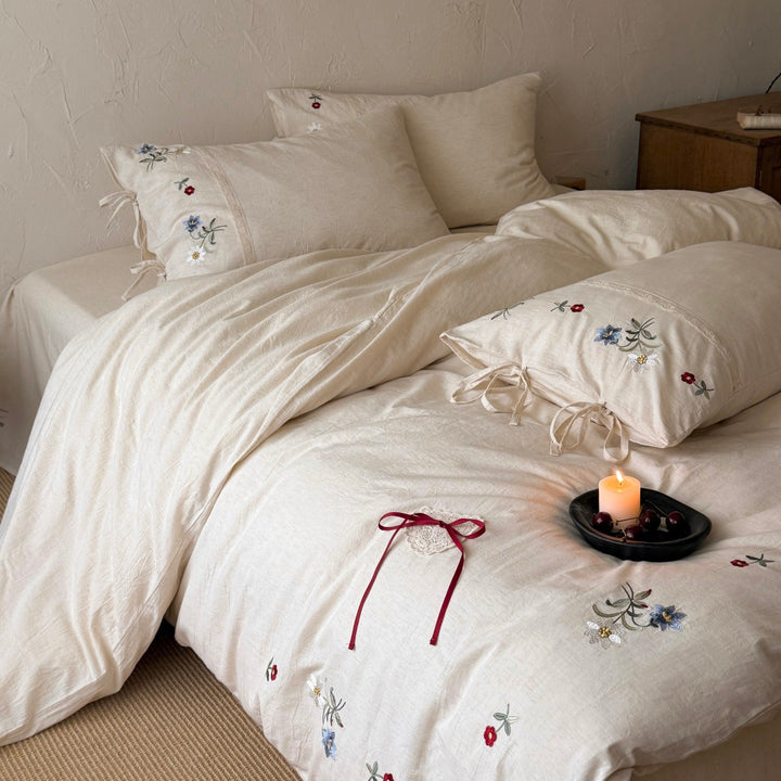 Romantic linen-cotton bedding set with delicate floral embroidery, tie loops and round cushion