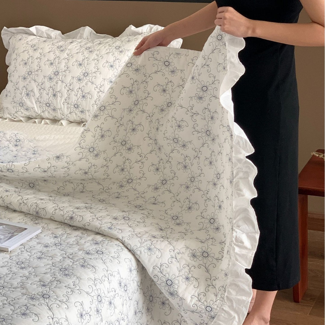 Padded quilted bedspread with a floral all-over pattern and ruffled edges