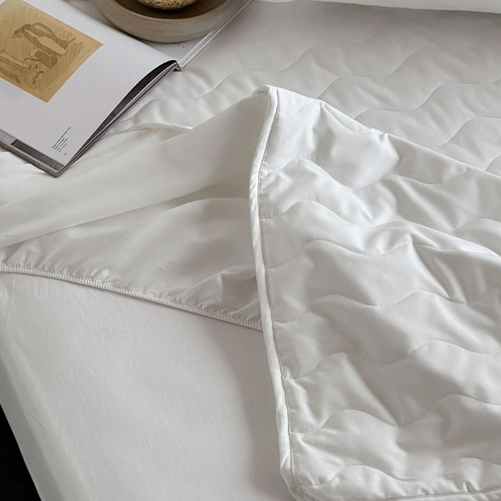 Padded mattress protector with all-round stretch and quilting