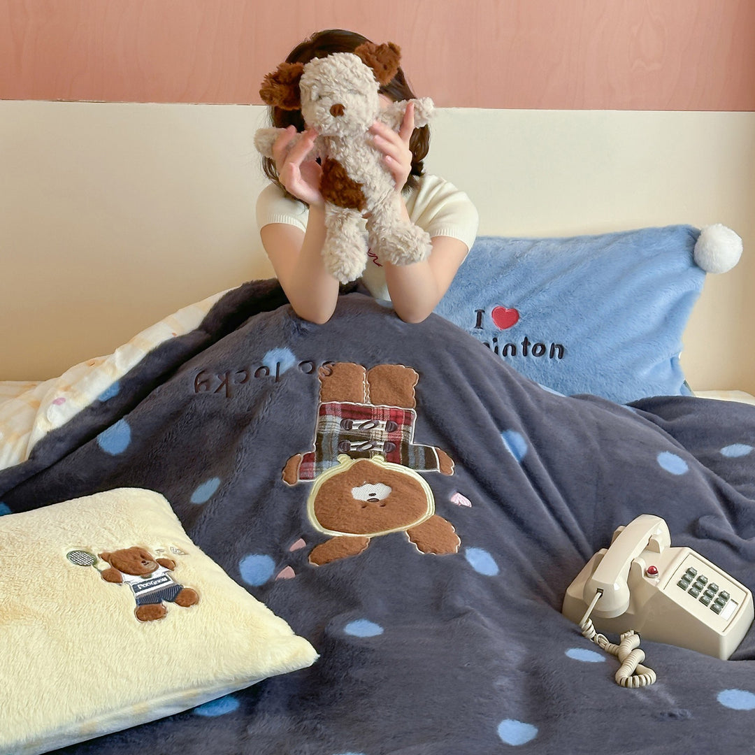 Plush bedspread with embroidered bear motif and pom-pom edge