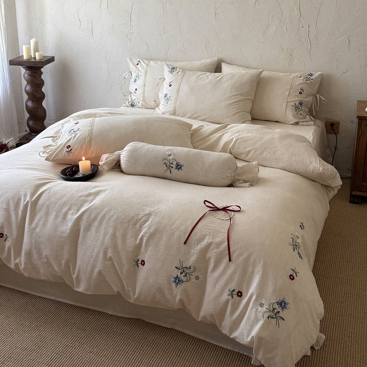 Romantic linen-cotton bedding set with delicate floral embroidery, tie loops and round cushion
