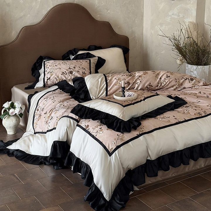 Satin bedding set with embroidered flower appliqués, layered flounce and decorative cushion