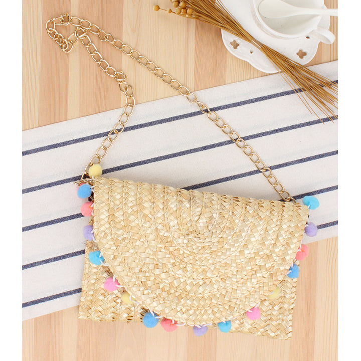 Clutch made of handwoven natural material with decorative pompons Stornfield