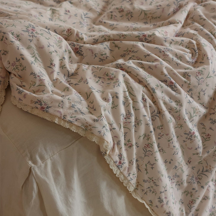 Quilted throw blanket made of cotton blend with delicate floral pattern and lace edge