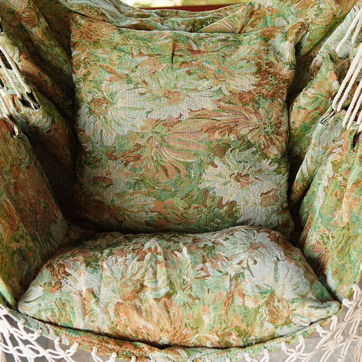 Woven hammock chair with padded floral cushions and macramé fringe Stornfield