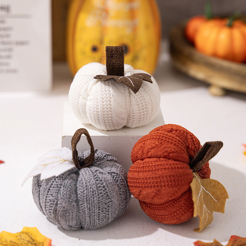 Knitted fabric pumpkin as autumn table decoration with felt leaf