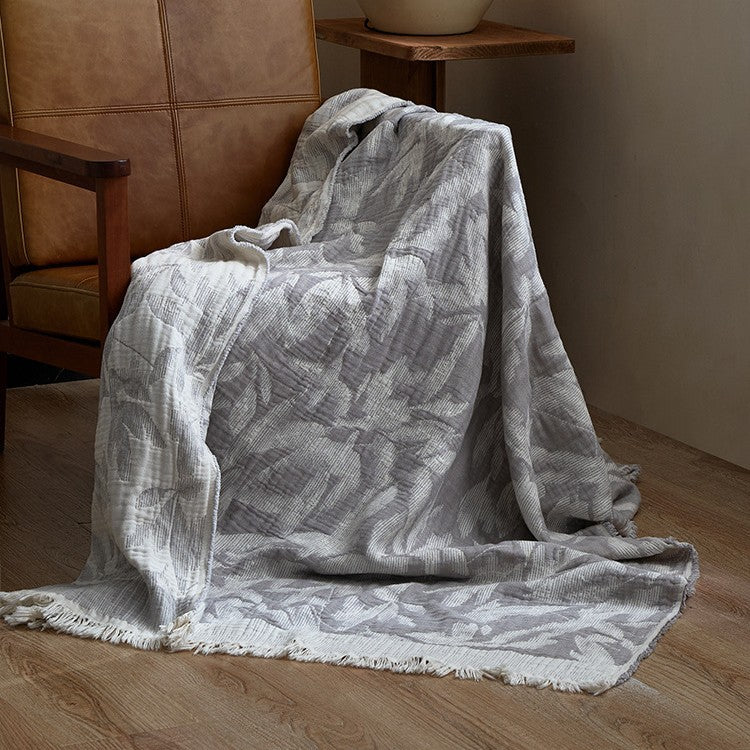 Large cozy living blanket made of cotton blend fabric with geometric jacquard pattern and fringed hem