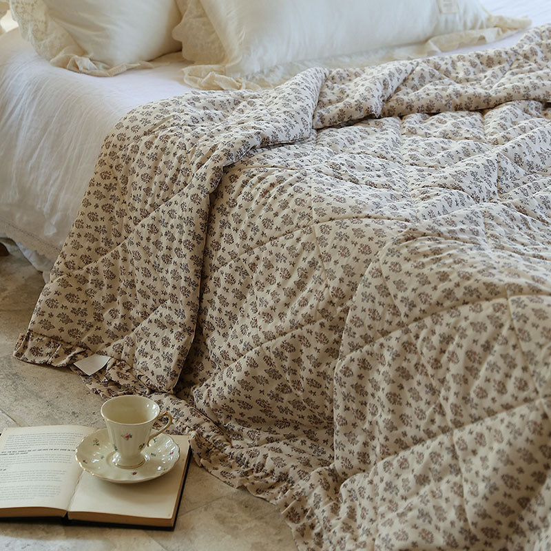 Lightly quilted throw blanket in vintage floral print with ruffled edge