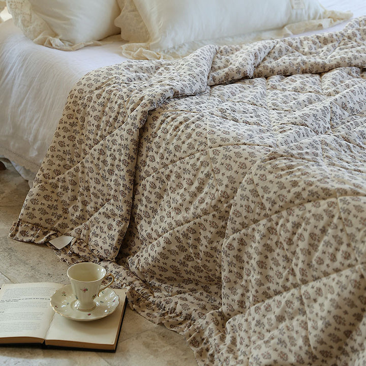 Lightly quilted throw blanket in vintage floral print with ruffled edge