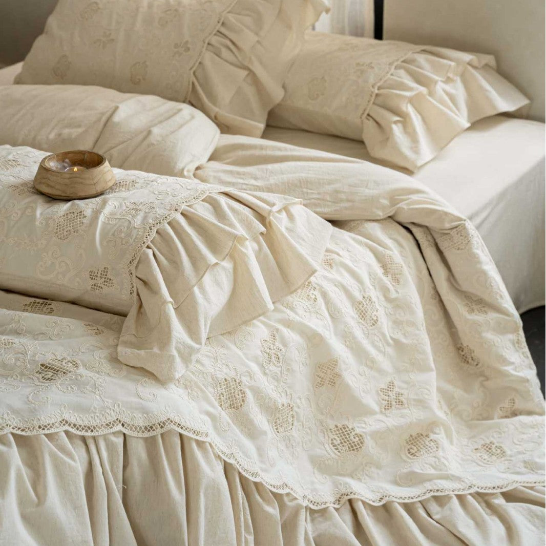 Romantic cotton bedding set in country house style with embroidered bedspread, ruffled bed skirt, and frill pillow.