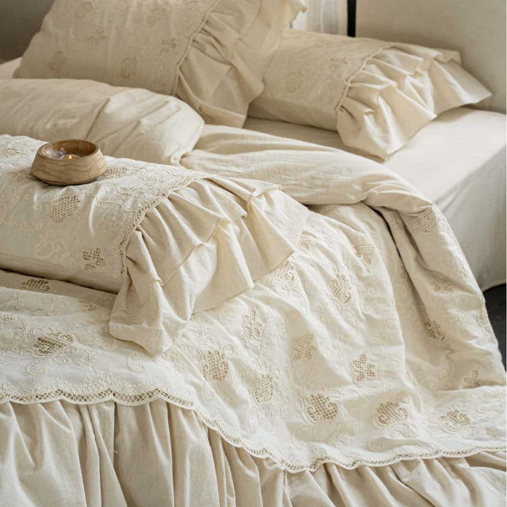 Romantic cotton bedding set in country house style with embroidered bedspread, ruffled bed skirt, and frill pillow.