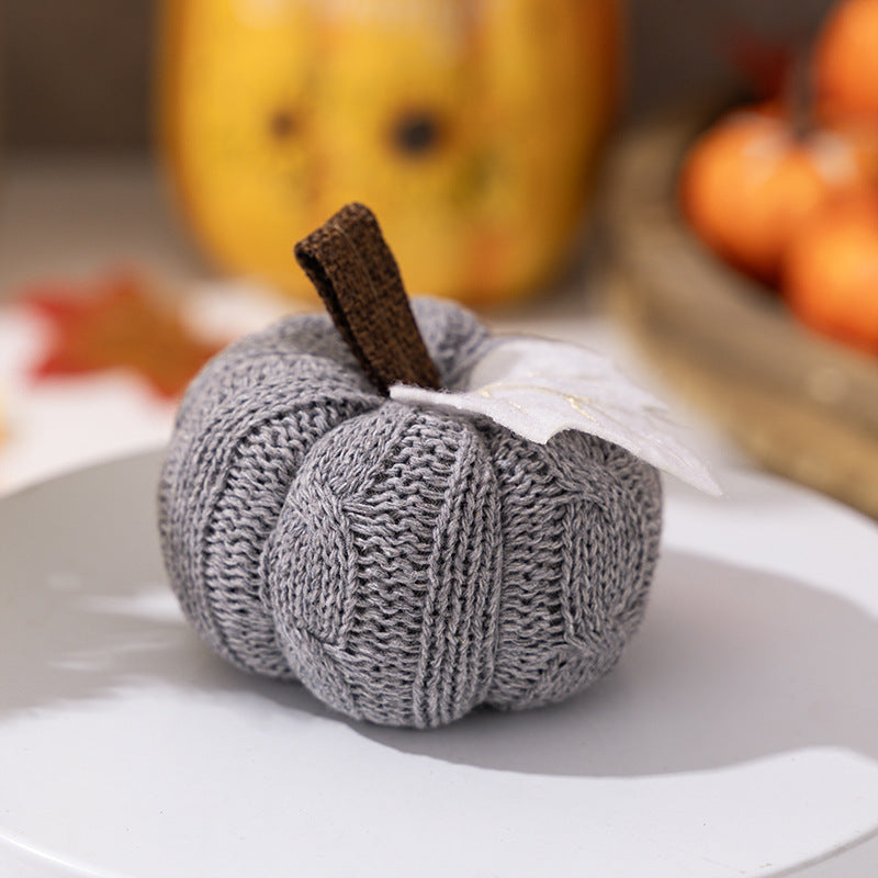 Knitted fabric pumpkin as autumn table decoration with felt leaf