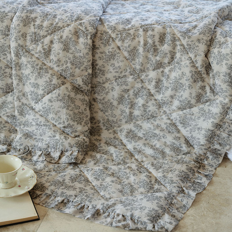 Lightly quilted throw blanket in vintage floral print with ruffled edge