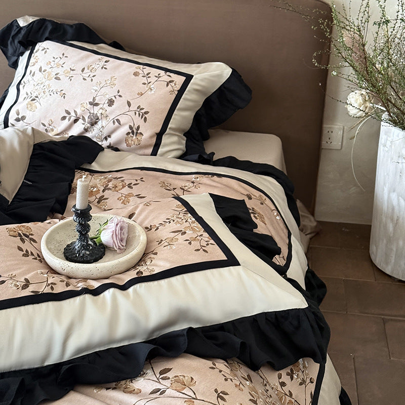 Satin bedding set with embroidered flower appliqués, layered flounce and decorative cushion