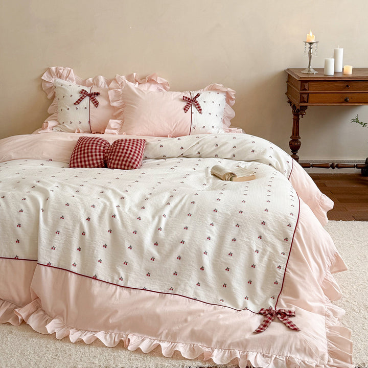 Playful ruffled bed set made of cotton muslin with embroidered cherries and checkered bows