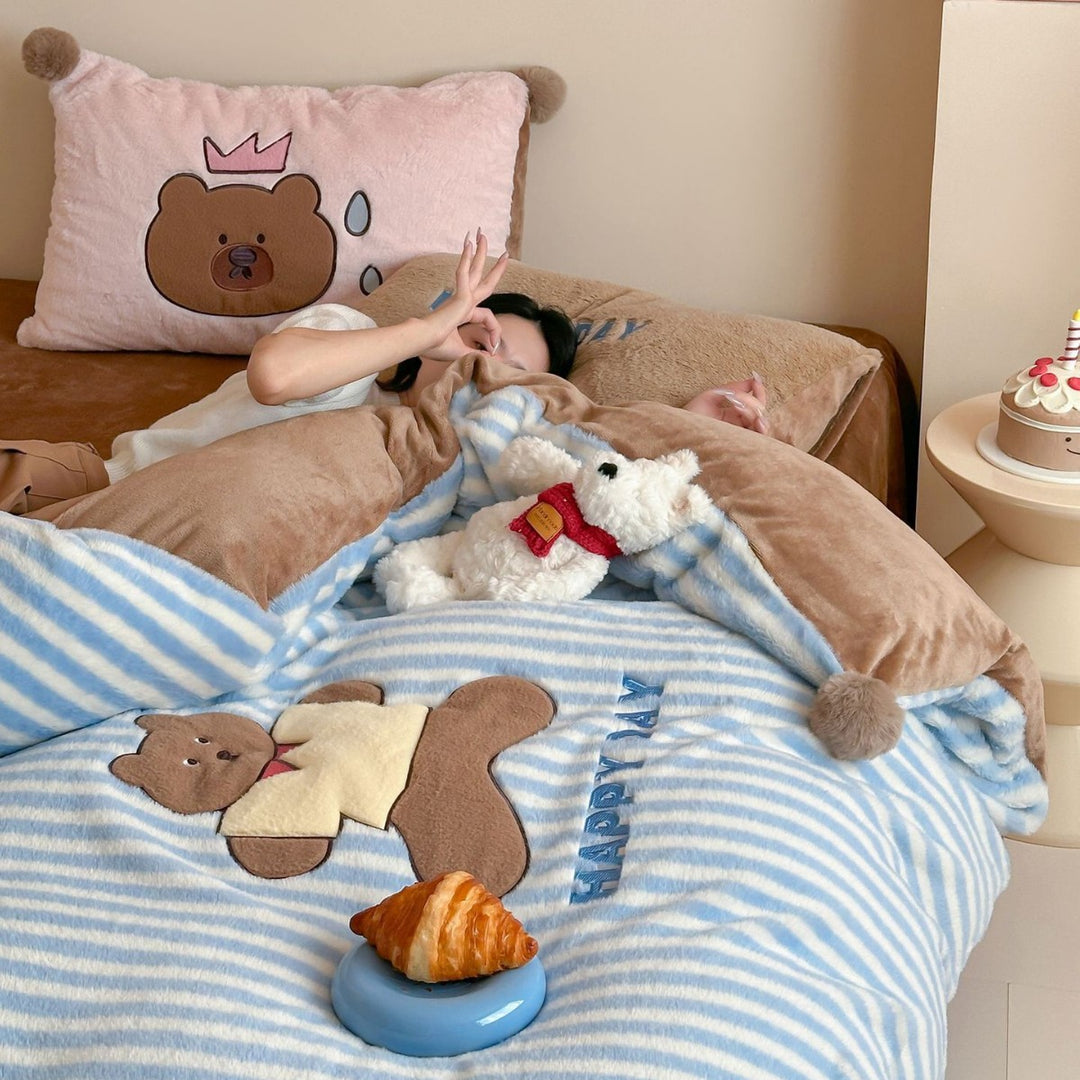 Striped plush throw blanket with decorative pom poms and appliqués