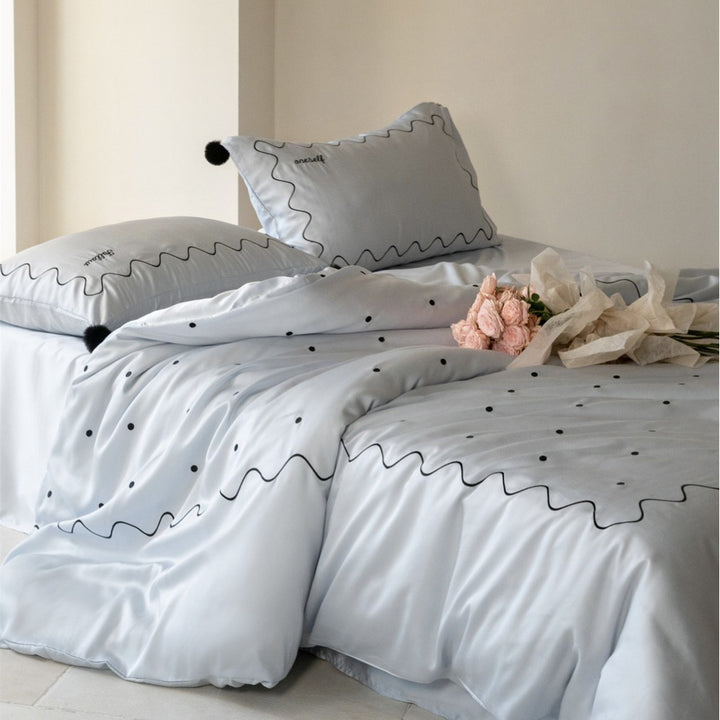 Bedding set made of cotton satin with wavy embroidery edge and pompom cushion