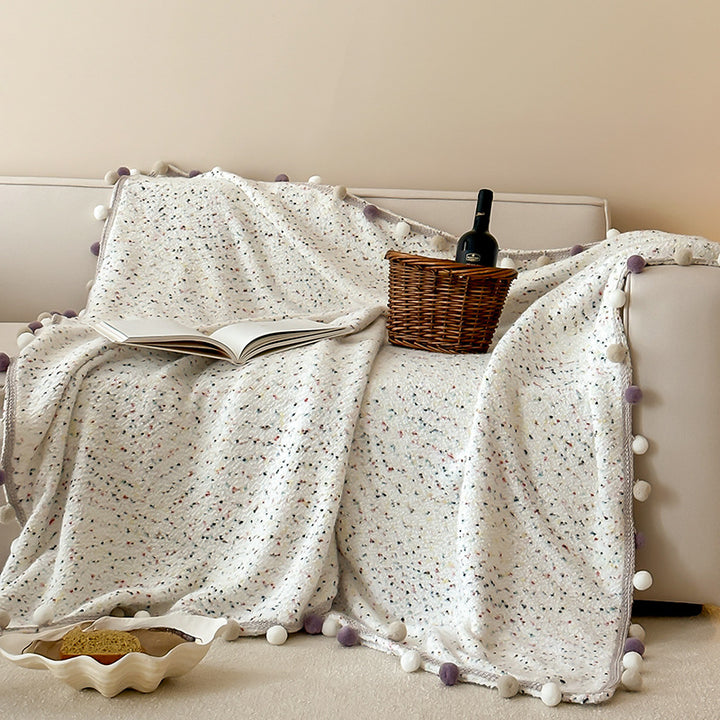 Cozy throw blanket with pom pom trim and mottled texture